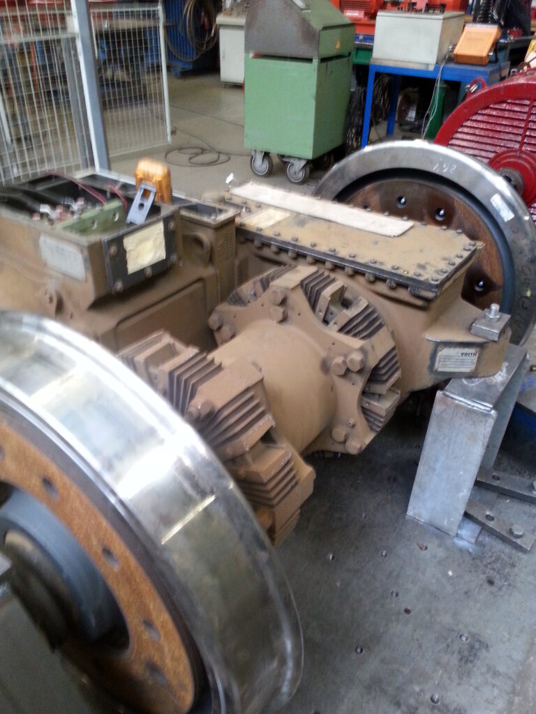 Triebradsatz eines Stadler GTW Zuges auf einem Prüfstand mit sichtbarem Fahrmotor (geöffneter Klemmkasten), Voith-Getriebe und Hohlwelle zwischen den beiden Eisenbahnrädern.