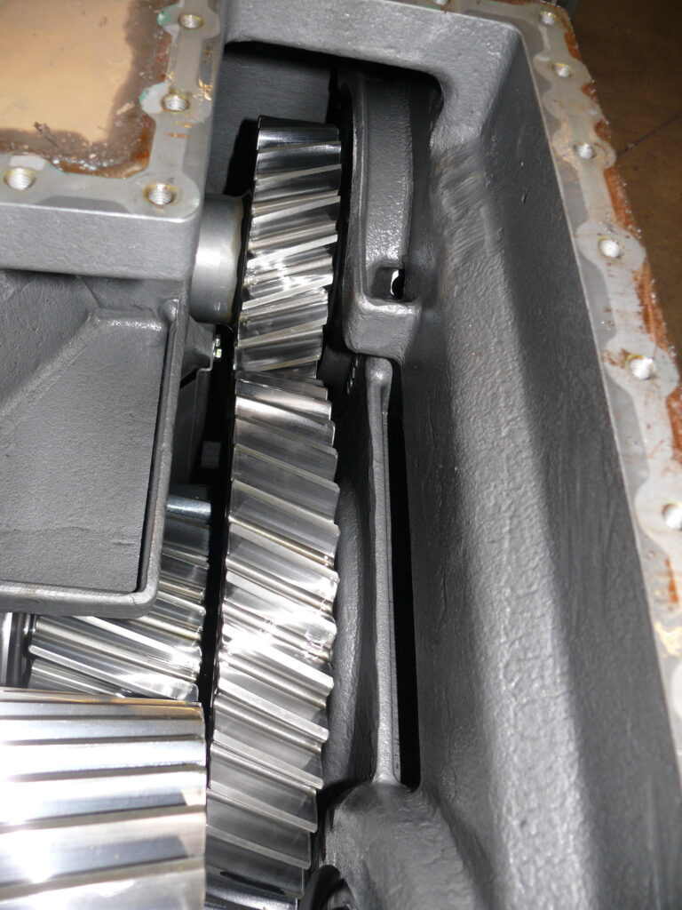 Geöffneter Blick in das Voith-Getriebegehäuse mit den ineinandergreifenden Schrägzahnrädern und deren glänzenden, polierten Metallzähnen.