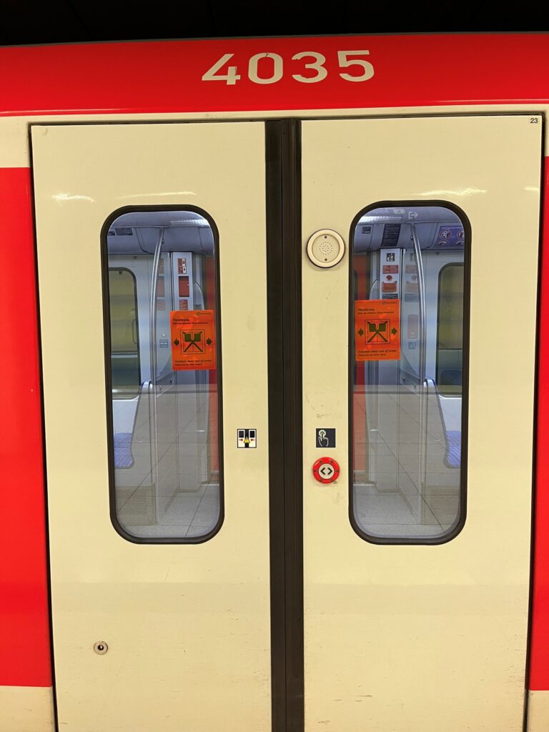 Geschlossene, weiß-rote Zugtüren eines S-Bahn-Zugs mit der Fahrzeugnummer 4035 und einem orangefarbenen Hinweisschild für eine vorübergehende Türstörung